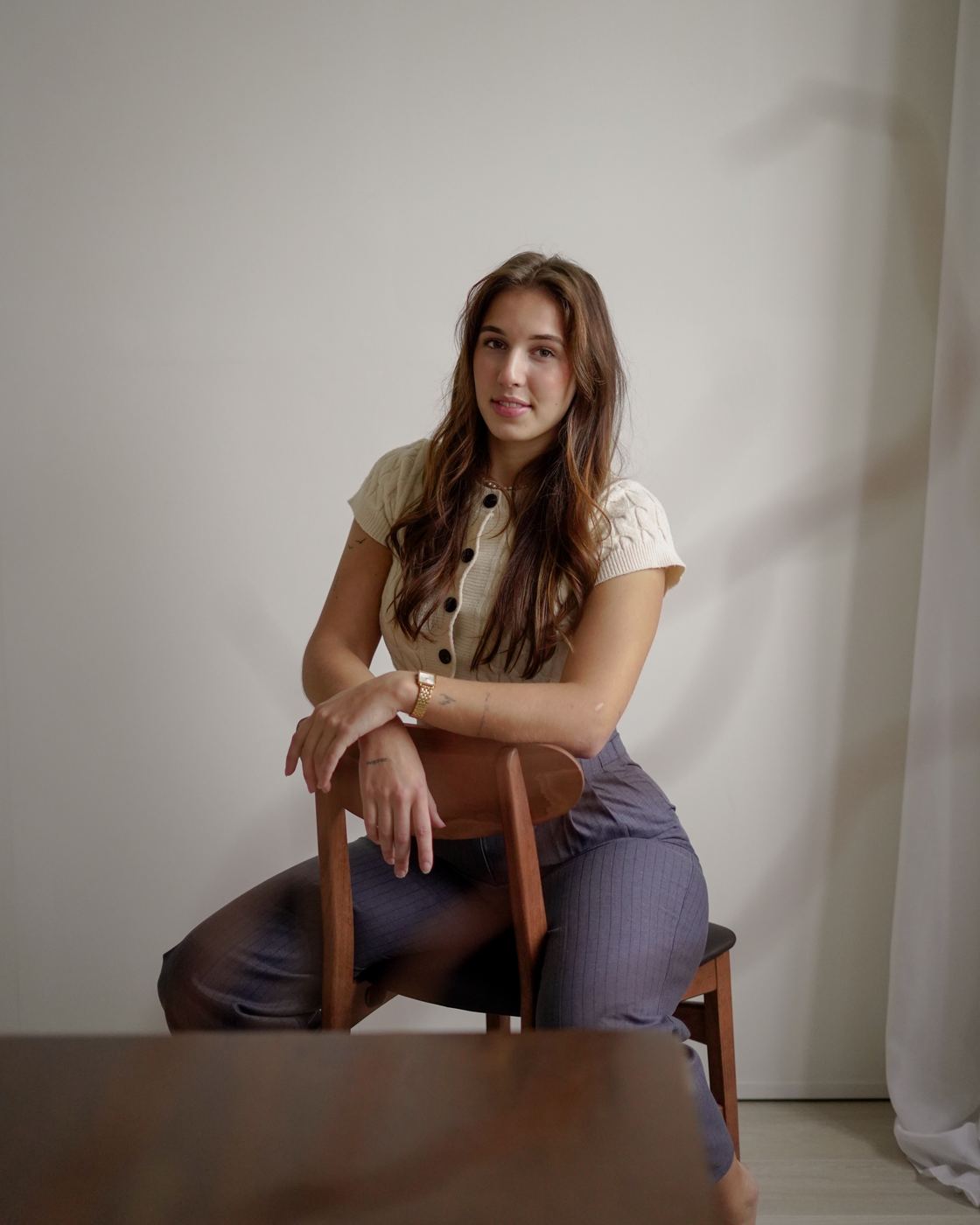 Voorbeeld van een portretshoot: ontspannen, achterstevoren op een stoel tegen een witte wand